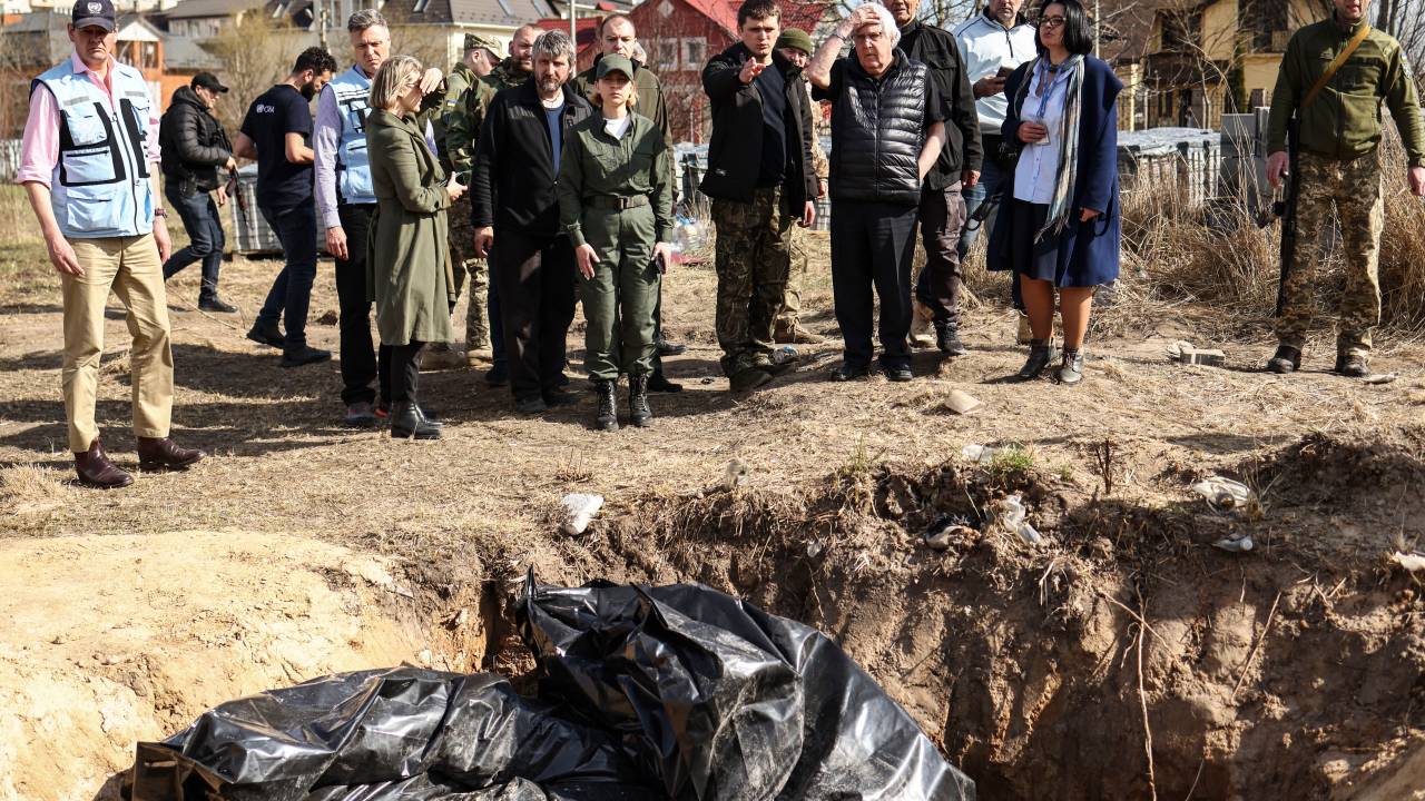 UN humanitarian chief Martin Griffiths (5th R) reacts at the site of a mass grave that Ukrainians had dug near a church on April 7, 2022 during his three-hour visit in Bucha, a day after he visited Moscow, where he met with officials to discuss the humanitarian situation in Ukraine, more than a month into the Russian invasion. - Griffiths said that investigators would probe civilian deaths uncovered after Russian troops withdrew. Evidence of civilian killings in Bucha and other towns around Kyiv - which Ukraine has blamed on Russian troops, allegations denied by Moscow - have shocked the world and triggered calls for new sanctions on Moscow. Russia's President has denied any responsibility for civilian deaths, accusing Ukrainian authorities of "crude and cynical provocations" in Bucha. (Photo by RONALDO SCHEMIDT / AFP)