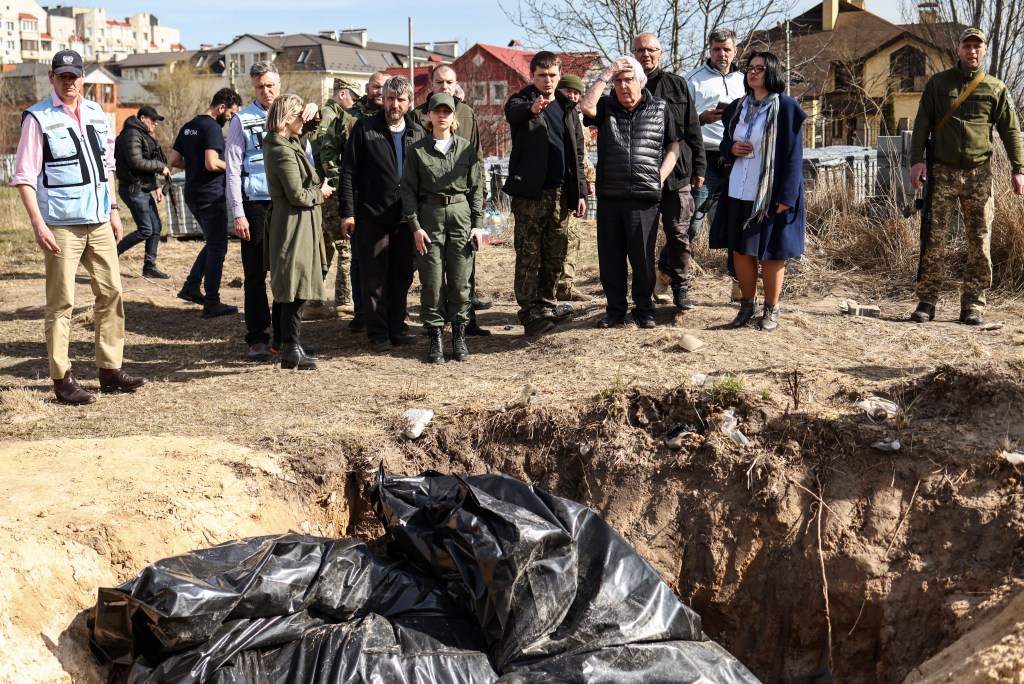 UN humanitarian chief Martin Griffiths (5th R) reacts at the site of a mass grave that Ukrainians had dug near a church on April 7, 2022 during his three-hour visit in Bucha, a day after he visited Moscow, where he met with officials to discuss the humanitarian situation in Ukraine, more than a month into the Russian invasion. - Griffiths said that investigators would probe civilian deaths uncovered after Russian troops withdrew. Evidence of civilian killings in Bucha and other towns around Kyiv - which Ukraine has blamed on Russian troops, allegations denied by Moscow - have shocked the world and triggered calls for new sanctions on Moscow. Russia's President has denied any responsibility for civilian deaths, accusing Ukrainian authorities of "crude and cynical provocations" in Bucha. (Photo by RONALDO SCHEMIDT / AFP)