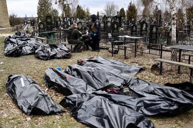 Corpos são alinhados para identificação por policiais forenses no cemitério de Bucha -
