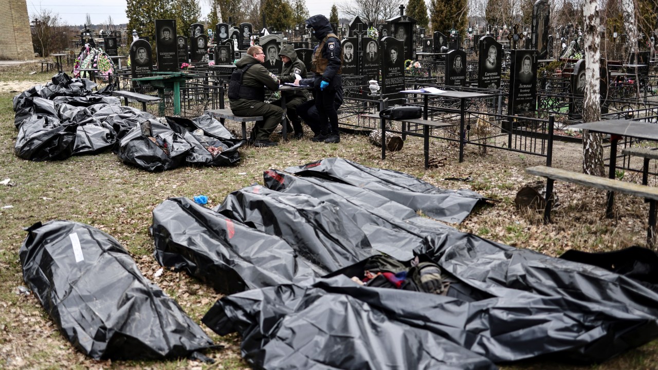 EDITORS NOTE: Graphic content / Bodies are lined up for identification by forensic personnel and police officers in the cemetery in Bucha, north of Kyiv, on April 6, 2022, after hundreds of civilians were found dead in areas from which Russian troops have withdrawn around Ukraine's capital, including the town of Bucha. - Located 30 kilometres (19 miles) northwest of Kyiv's city centre, the town of Bucha was occupied by Russian forces on February 27 in the opening days of the war and remained under their control for a month. After the bombardments stopped, Ukrainian forces were able to retake the town. Large numbers of bodies of men in civilian clothing have since been found in the streets. (Photo by RONALDO SCHEMIDT / AFP)