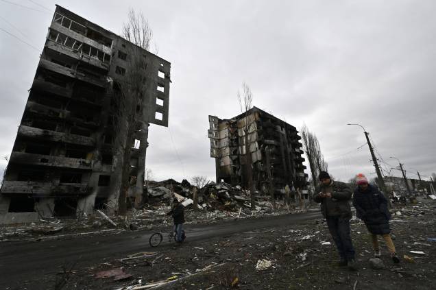 Moradores locais passam por um prédio destruído na cidade de Borodianka -