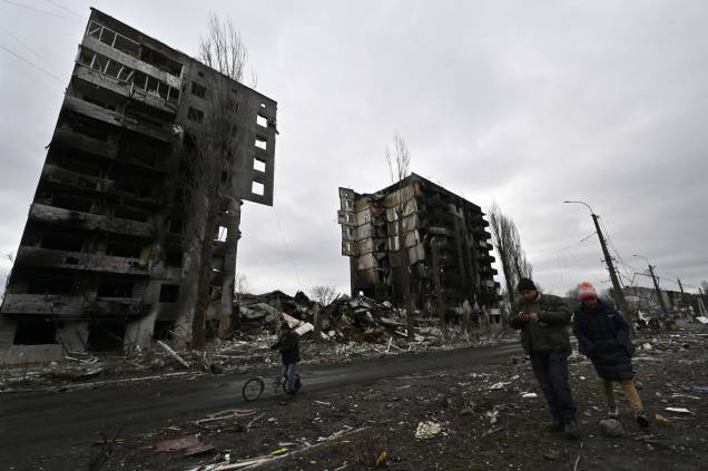 Moradores locais passam por um prédio destruído na cidade de Borodianka - Moradores locais passam por um prédio destruído na cidade de Borodianka -