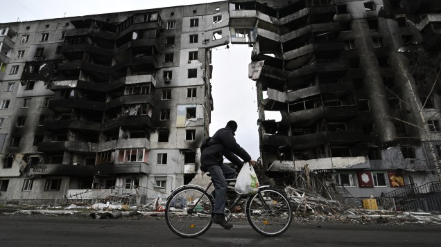 Um ciclista passa por um prédio destruído na cidade de Borodianka, a noroeste de Kiev -