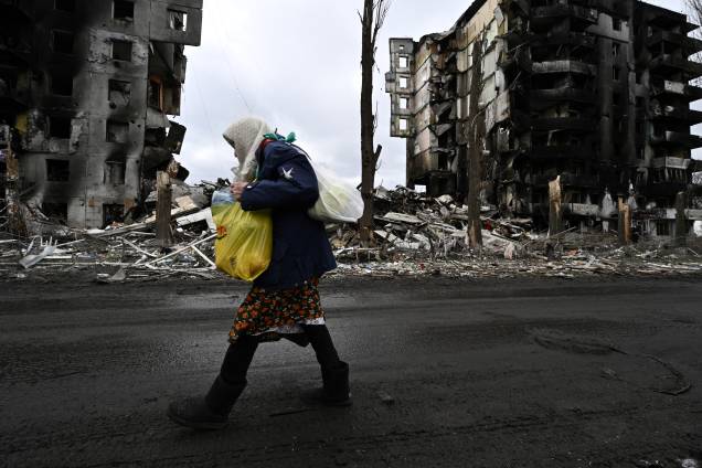 Uma mulher caminha em frente a prédios destruídos na cidade de Borodianka -