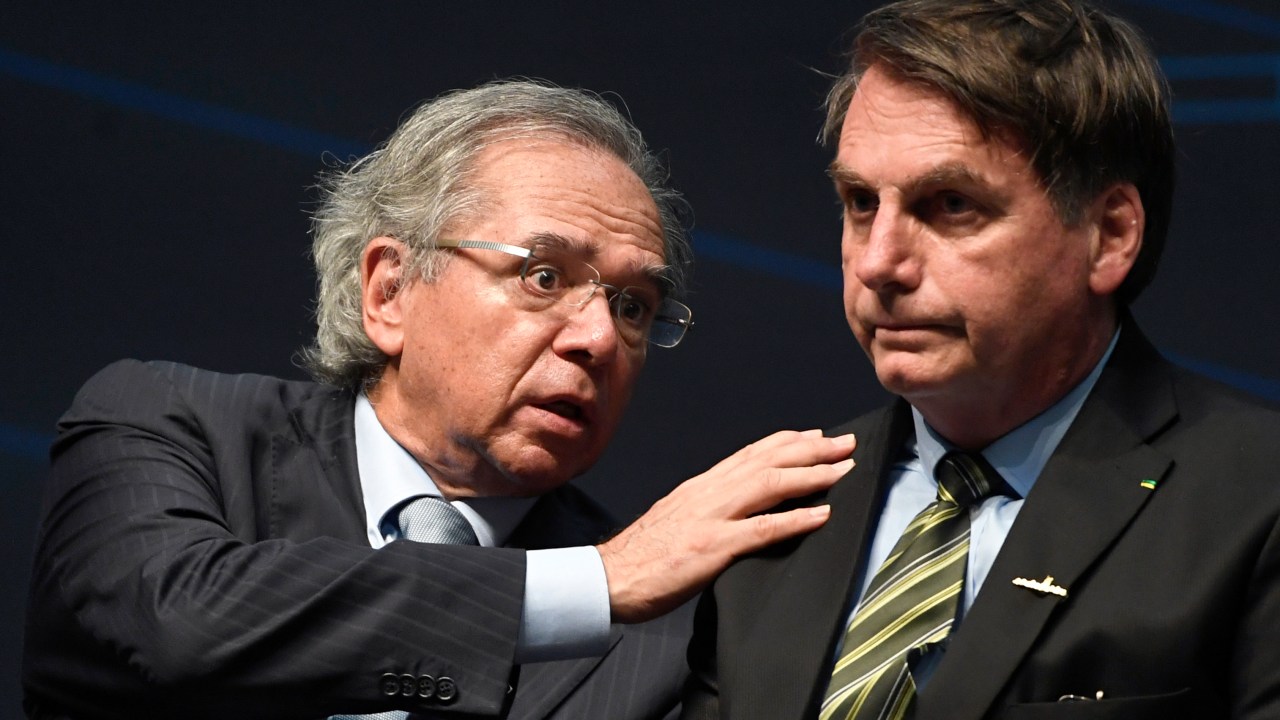 (FILES) In this file picture taken on October 11, 2019 Brazil's Economy Minister Paulo Guedes (L) speaks with Brazilian President Jair Bolsonaro during the ceremony marking the assembly of the parts of Brazil's new Navy submarine Humaita (SBR-2), at the Itaguai Navy Complex in Rio de Janeiro, Brazil. - Guedes, the powerful free-market guru to far-right President Jair Bolsonaro, said on August 11, 2020 that two of his top deputies had resigned in a "stampede." The minister is battling to steer Brazil back toward an agenda of austerity and privatizations -- no easy task during a pandemic that has hammered the country and forced the government into months of emergency spending. Guedes has now lost eight top aides since Bolsonaro took office in January 2019, nearly half his original team. (Photo by Mauro PIMENTEL / AFP)