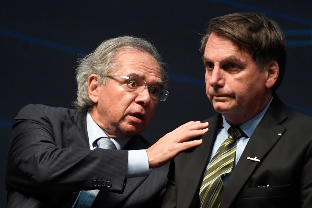 (FILES) In this file picture taken on October 11, 2019 Brazil's Economy Minister Paulo Guedes (L) speaks with Brazilian President Jair Bolsonaro during the ceremony marking the assembly of the parts of Brazil's new Navy submarine Humaita (SBR-2), at the Itaguai Navy Complex in Rio de Janeiro, Brazil. - Guedes, the powerful free-market guru to far-right President Jair Bolsonaro, said on August 11, 2020 that two of his top deputies had resigned in a "stampede." The minister is battling to steer Brazil back toward an agenda of austerity and privatizations -- no easy task during a pandemic that has hammered the country and forced the government into months of emergency spending. Guedes has now lost eight top aides since Bolsonaro took office in January 2019, nearly half his original team. (Photo by Mauro PIMENTEL / AFP)