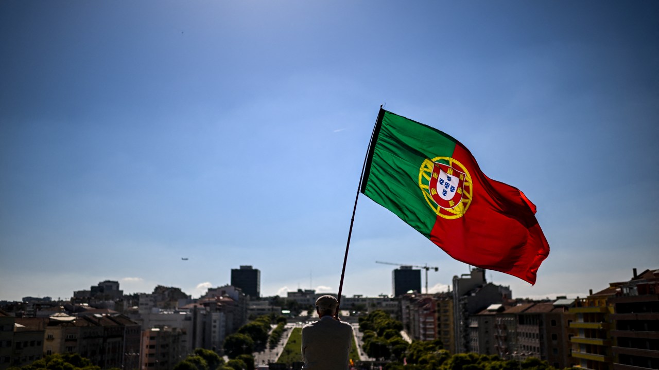 A man holds a Portugues flag during a rally marking the International Workers' Day in Lisbon on May 1, 2022. (Photo by PATRICIA DE MELO MOREIRA / AFP)