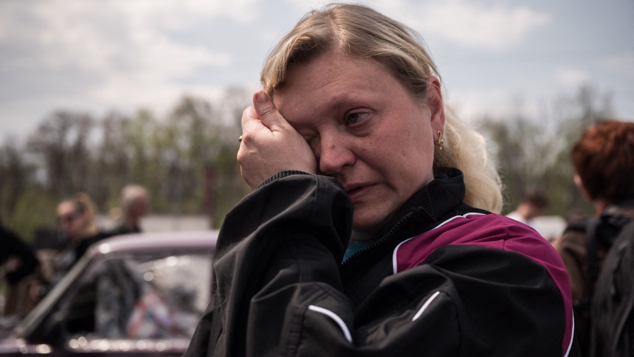 Nadiajda Vorotylina reage após chegar com sua família da cidade sitiada de Mariupol em seu próprio veículo, à frente de um esperado comboio humanitário em uma área de registro e processamento de deslocados internos na Ucrânia, em Zaporizhzhia, em 2 de maio de 2022. - A família ficou em um barco por um mês no porto de Mariupol, onde seu marido trabalhava, para evitar brigas, antes de fugir. (Foto de Ed JONES/AFP)