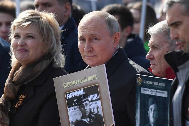 O presidente russo Vladimir Putin e outros participantes carregam retratos de seus parentes - soldados da Segunda Guerra Mundial - enquanto participam da marcha do Regimento Imortal na Praça Vermelha, no centro de Moscou -