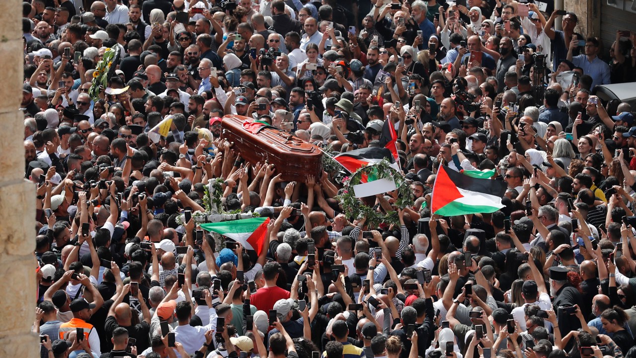 Palestinian mourners wave national flags as they carry the casket of slain Al-Jazeera journalist Shireen Abu Akleh, during her funeral procession near Jaffa Gate, one of the main gates of the Old City of Jerusalem, on May 13, 2022. - Abu Akleh, who was shot dead on May 11, 2022 while covering a raid in the Israeli-occupied West Bank, was among Arab media's most prominent figures and widely hailed for her bravery and professionalism. (Photo by Ahmad GHARABLI / AFP)
