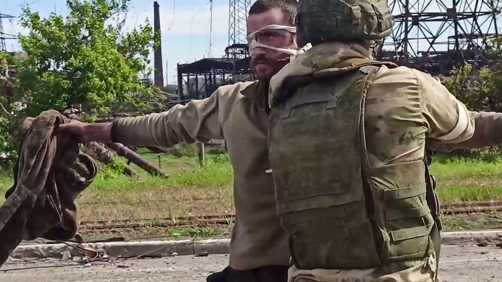 Esta captura de tela obtida de um vídeo divulgado pelo Ministério da Defesa da Rússia mostra um soldado ucraniano sendo revistado por um militar pró-Rússia depois de deixar a siderúrgica Azovstal - 17/05/2022