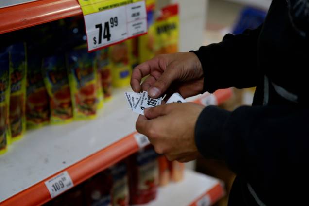Um comerciante de um supermercado, na cidade de Buenos Aires alterando os preços de produtos. A economia da Argentina sentiu muito os efeitos da pandemia e às restrições sanitárias adotadas para conter a Covid-19.