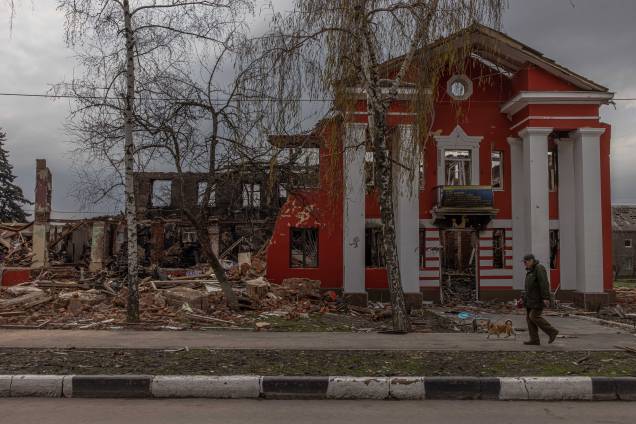 Um homem passa com um cachorro pelo liceu de tecnologia e comércio de alimentos destruído, após o recente bombardeio da artilharia russa, em Kharkiv, nordeste da Ucrânia, 14 de abril de 2022. Um homem passa com um cachorro pelo liceu de tecnologia e comércio de alimentos destruído, após o recente bombardeio da artilharia russa, em Kharkiv, nordeste da Ucrânia, 14 de abril de 2022.