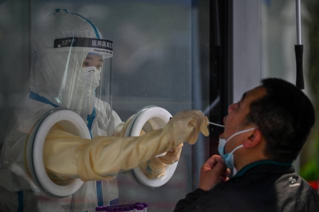 Um profissional de saúde, coleta uma amostra de um homem durante um bloqueio de Coronavírus Covid-19 no distrito de Jing'an, em Xangai, em 27/05/2022.