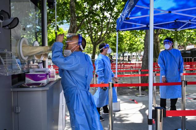 Um profissional de saúde coleta uma amostra de um colega para testar o Coronavírus Covid-19 no distrito de Jing'an, em Xangai, em 31/05/2022, enquanto a cidade se prepara para suspender mais restrições após dois meses de restrições pesadas.