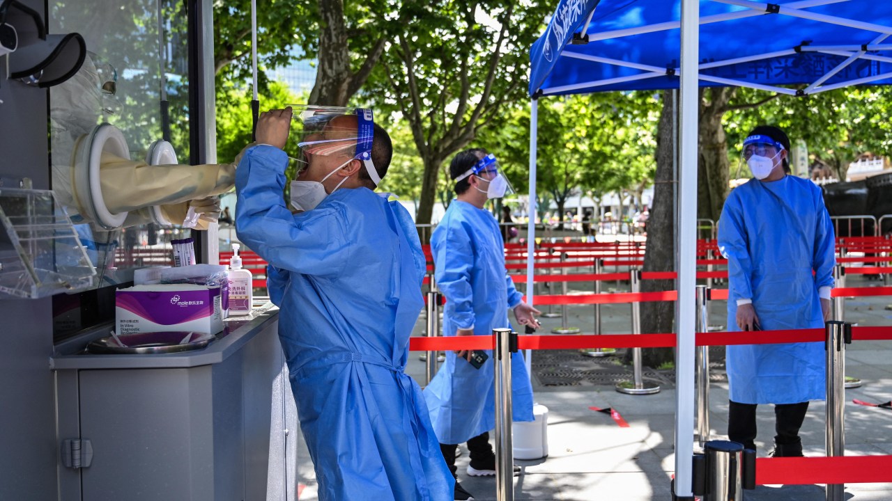 Um profissional de saúde coleta uma amostra de cotonete de um colega para testar o coronavírus Covid-19 no distrito de Jing'an, em Xangai, em 31 de maio de 2022, enquanto a cidade se prepara para suspender mais restrições após dois meses de restrições pesadas. (Foto de Hector RETAMAL/AFP)