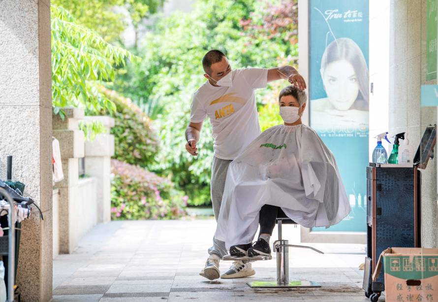 Um voluntário da comunidade, corta o cabelo de um residente em um complexo residencial, durante o bloqueio de Covid-19 no distrito de Pudong, em Xangai, em 1º de maio de 2022.