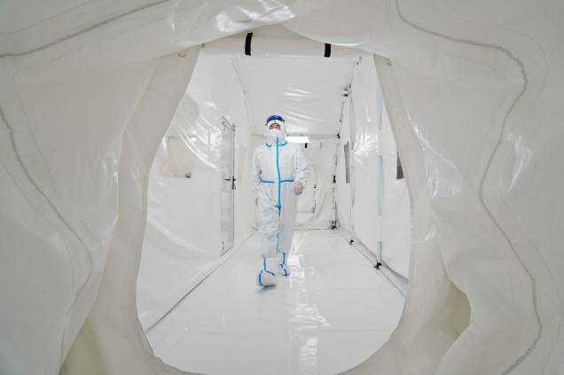 Foto de 17 de março de 2022, mostra um funcionário, usando equipamento de proteção individual, caminhando no laboratório Fire Eye, uma instalação temporária de testes de Coronavírus Covid-19 na província de Shandong, leste da China.