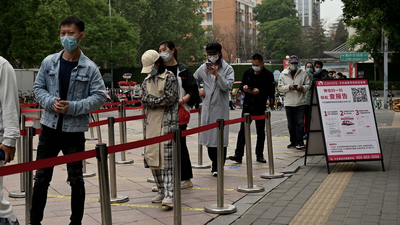Pessoas fazem fila para fazer um teste de cotonete para o coronavírus Covid-19 em um local de coleta de cotonetes em Pequim em 10 de maio de 2022. - Milhões de pessoas em Pequim ficaram em casa em 9 de maio, enquanto a capital da China tenta afastar um surto de Covid-19 com rastejantes restrições de movimento. (Foto de Noel Celis/AFP)