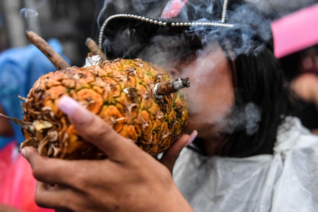 Uma mulher fuma Maconha em um abacaxi durante a Marcha Global da Maconha, exigindo a descriminalização da erva em Medellín, região de Antioquia, Colômbia, em 7 de maio de 2022.