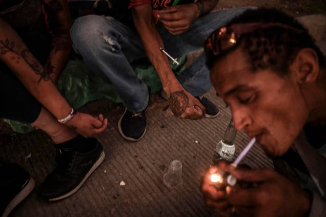 Viciados, fumam Crack, cocaína de baixo grau misturada com pasta de coca e outras substâncias, enquanto outros se injetam com heroína no centro de Medellín, Colômbia, em 1º de março de 2022.