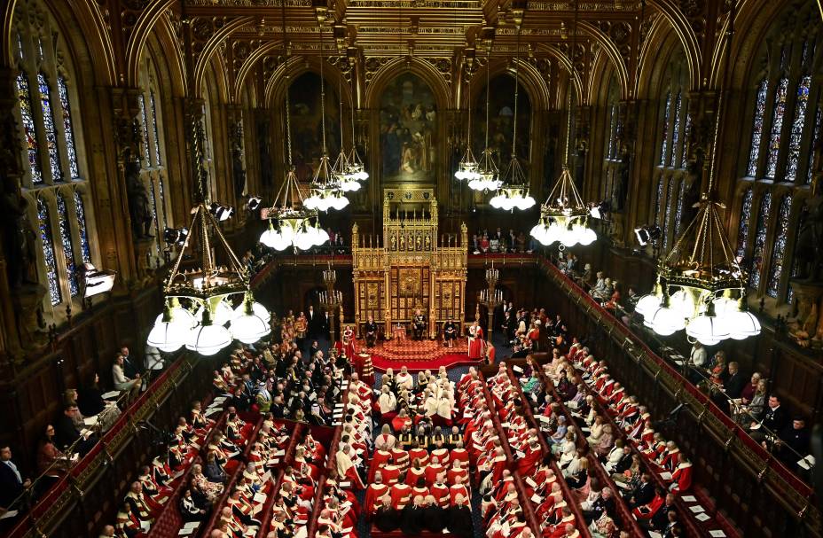 O príncipe britânico Charles, Príncipe de Gales, lê o Discurso da Rainha sentado ao lado da Coroa do Estado Imperial da Grã-Bretanha, Camilla Duquesa da Cornualha e do Britânico Príncipe William, Duque de Cambridge na Câmara dos Lordes, durante a Abertura Estadual do Parlamento, em Londres, em 10 de maio de 2022.