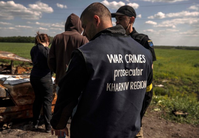 Policiais e investigadores de crimes de guerra em visita à área de um possível crime contra Volodymyr Kotenko, de 38 anos, cometido pelo exército russo na área de Kharkov, em 23/05/2022.