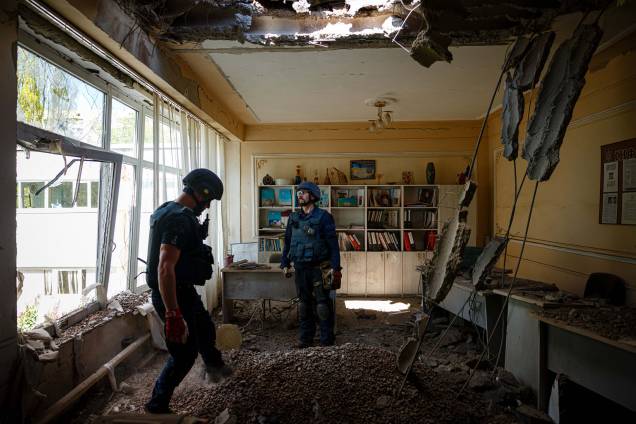 Membros de uma equipe do Serviço de Emergência do Estado da Ucrânia verificam se há dispositivos não detonados em um prédio escolar após o bombardeio russo em Kharkiv, leste da Ucrânia, em 28 de abril de 2022.