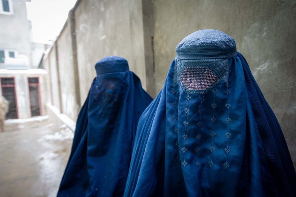 PUL-E ALAM, AFGHANISTAN -- JANUARY 17: Two women wearing burqas pause for a portrait after having their ration cards checked, as the UN World Food Program (WFP) distributes a critical monthly food ration, with food largely supplied by the US Agency for International Development (USAID), to 400 families south of Kabul in Pul-e Alam, Afghanistan, on January 17, 2022. This food delivery to Logar province comes as the UN warns that 23 million Afghans, more than half the population, are on the verge of famine, following a severe drought and as winter deepens, while the US and World Bank have only partially released funds frozen when the Taliban took control of Afghanistan in August 2021. The UN has made an emergency appeal for $5.5 billion to feed the hungry and forestall further economic collapse. (Photo by Scott Peterson/Getty Images)