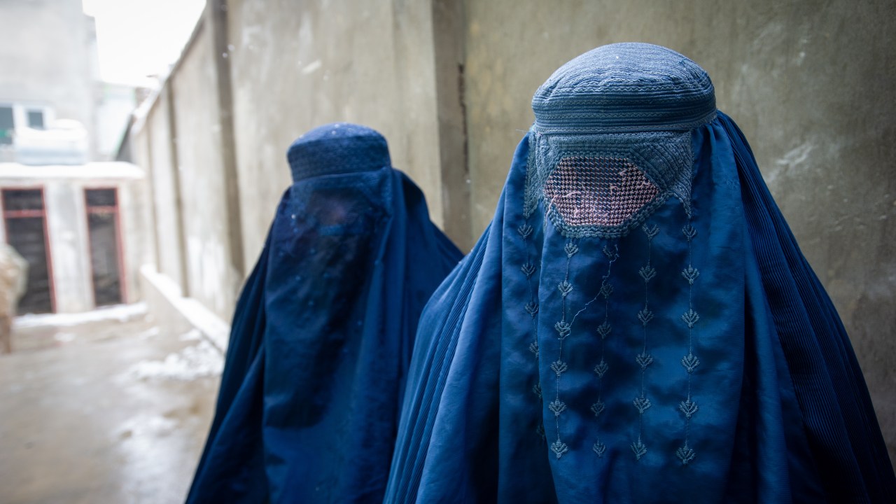PUL-E ALAM, AFGHANISTAN -- JANUARY 17: Two women wearing burqas pause for a portrait after having their ration cards checked, as the UN World Food Program (WFP) distributes a critical monthly food ration, with food largely supplied by the US Agency for International Development (USAID), to 400 families south of Kabul in Pul-e Alam, Afghanistan, on January 17, 2022. This food delivery to Logar province comes as the UN warns that 23 million Afghans, more than half the population, are on the verge of famine, following a severe drought and as winter deepens, while the US and World Bank have only partially released funds frozen when the Taliban took control of Afghanistan in August 2021. The UN has made an emergency appeal for $5.5 billion to feed the hungry and forestall further economic collapse. (Photo by Scott Peterson/Getty Images)