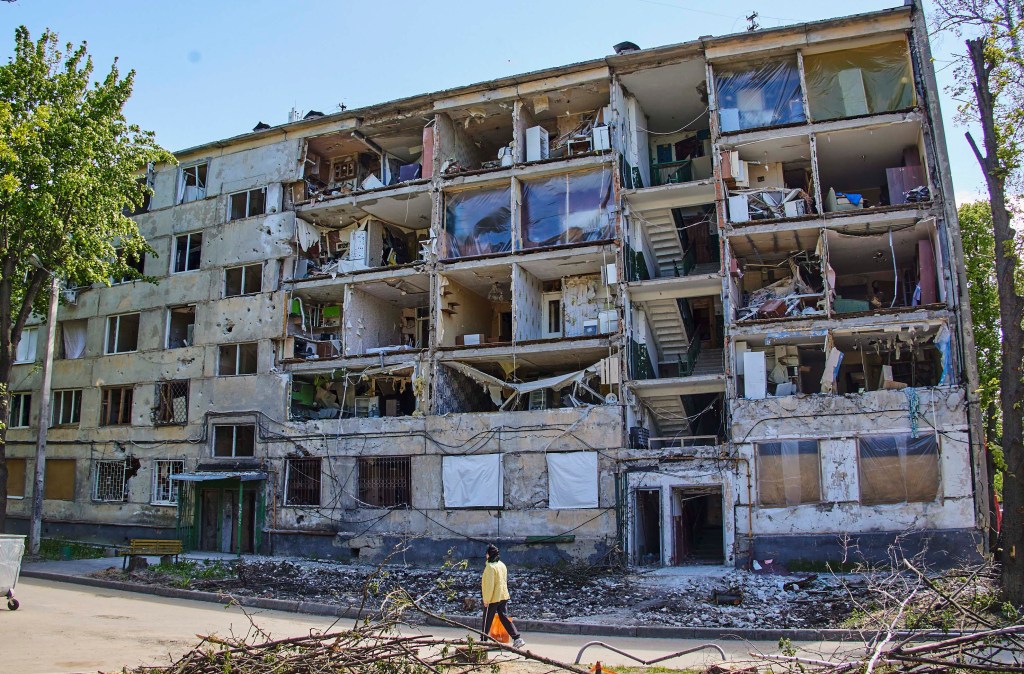 Kharkiv (Ucrânia), 12/05/2022.- Uma mulher passa por um edifício residencial danificado durante o bombardeio de Kharkiv, Ucrânia, 12 de maio de 2022. O Ministério da Defesa da Ucrânia anunciou em 10 de maio que as tropas ucranianas haviam recapturado Kharkiv e aldeias ao norte e nordeste da cidade das forças russas e os empurrou de volta para a fronteira. A cidade de Kharkiv, a segunda maior da Ucrânia, testemunhou repetidos ataques aéreos das forças russas. Em 24 de fevereiro, tropas russas invadiram o território ucraniano iniciando um conflito que provocou destruição e uma crise humanitária. (Rússia, Ucrânia) EFE/EPA/SERGEY KOZLOV