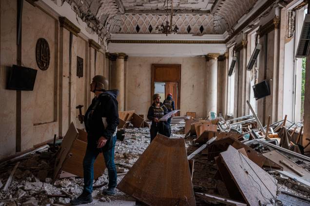 Engenheiros de construção examinam um edifício danificado da Administração Estatal Regional de Kharkiv em 16 de maio de 2022, que foi fortemente bombardeado durante a invasão russa da Ucrânia.