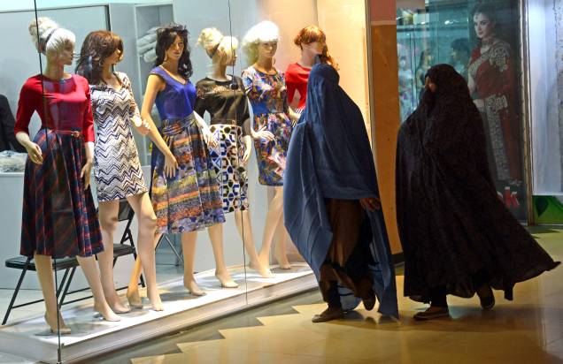 Mulheres afegãs olham uma vitrine de roupas femininas em uma loja em Herat, Afeganistão.