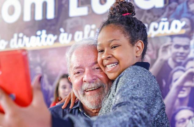 30/04/2022 - Ex-presidente Lula com criança no colo faz selfie, visita o bairro Brasilândia, em São Paulo, para discutir o custo de vida e o direito à alimentação, em encontro com moradores.