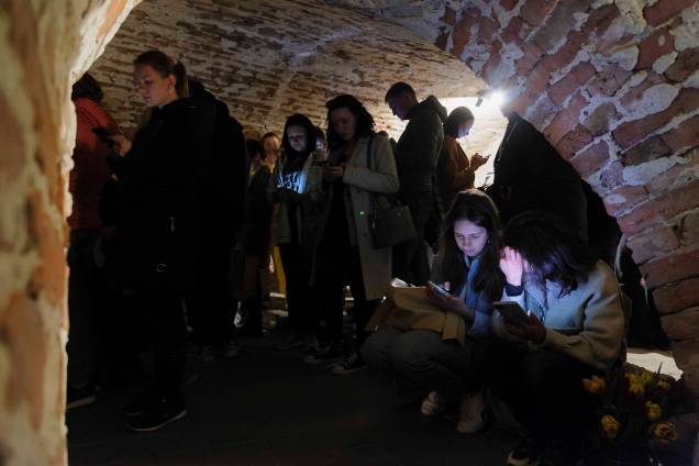 Pessoas compartilham espaços em um  porão de um edifício histórico que está sendo usado como abrigo antiaéreo durante um alerta de ataque aéreo na cidade de Lviv, no oeste da Ucrânia.
