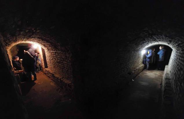 Pessoas se acomodam numa galeria subterrânea de um edifício histórico que está sendo usado como abrigo antiaéreo, durante um alerta de ataque aéreo na cidade de Lviv.