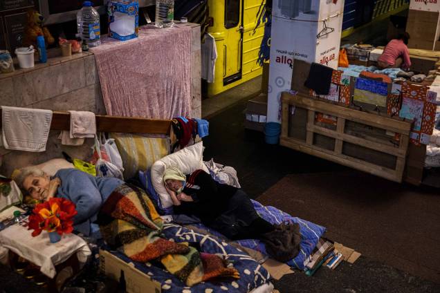 Mulheres deitadas em camas improvisadas, enquanto se abrigam e vivem em uma estação de metrô em Kharkiv, leste da Ucrânia, em 30 de abril de 2022.