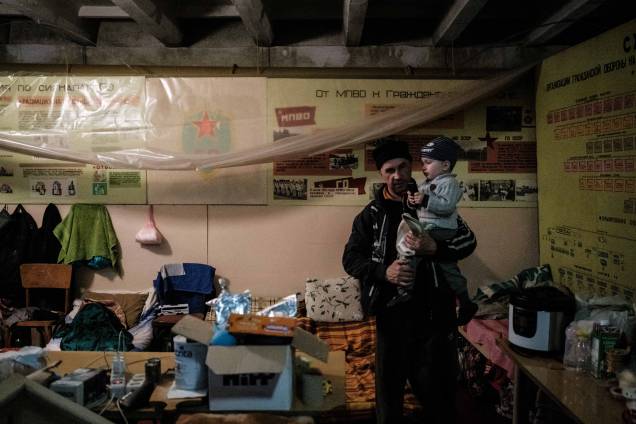 Vitalii (50 anos),  segura seu filho Kiril, 2 anos, no bunker da fábrica Ostchem em Severodonetsk, leste da Ucrânia, em 27 de abril de 2022, em meio à invasão dos russos.