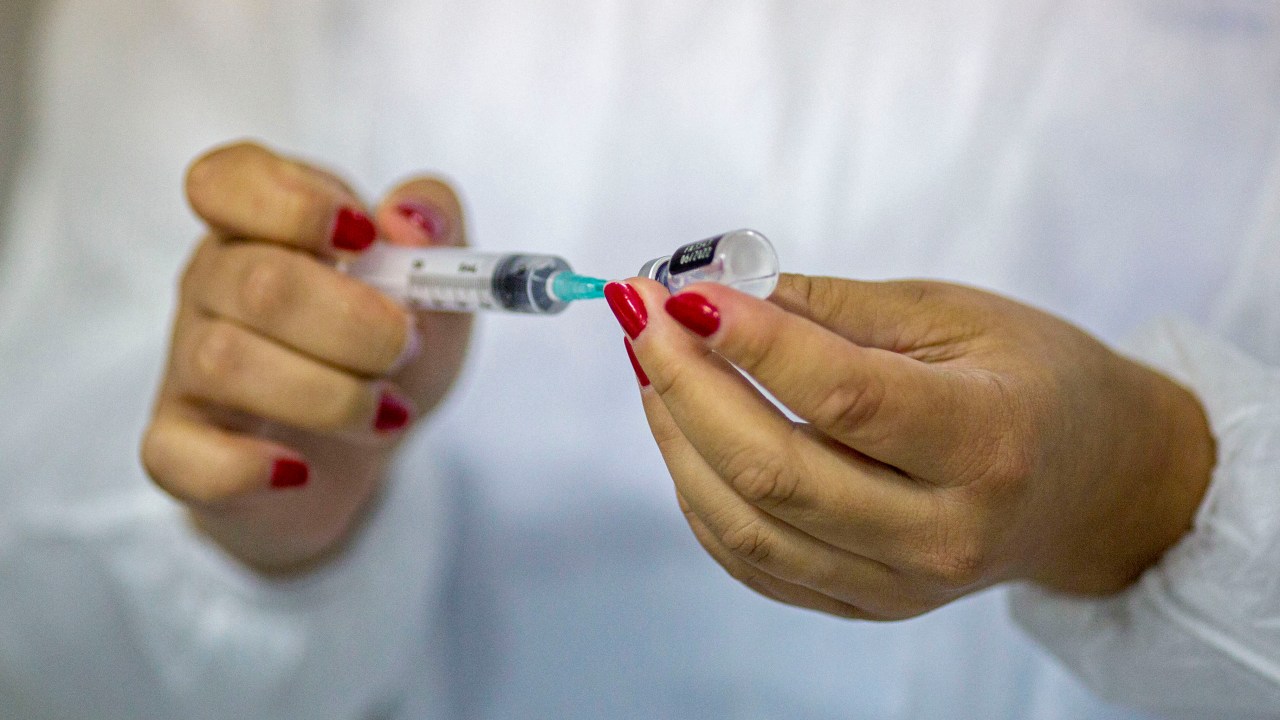 A nurse loads a syringe with a dose of a vaccine against COVID-19 in a tent at Copacabana beach in Rio de Janeiro, Brazil, on December 31, 2021. (Photo by DANIEL RAMALHO / AFP)