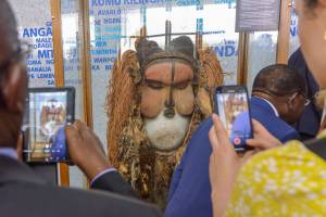 People take pictures of a ceremonial mask handed to President of the Democratic Republic of the Congo Felix Tshisekedi (not seen) by Belgium's King Philippe (not seen) during a ceremony at the National Museum of the Democratic Republic of the Congo in Kinshasa on June 8, 2022. - Belgium's King Phillipe visited DRC's national museum in Kinshasa, established in 2019, where he handed over a ceremonial mask the ethnic Suku group use in initiation rites. The mask is on 