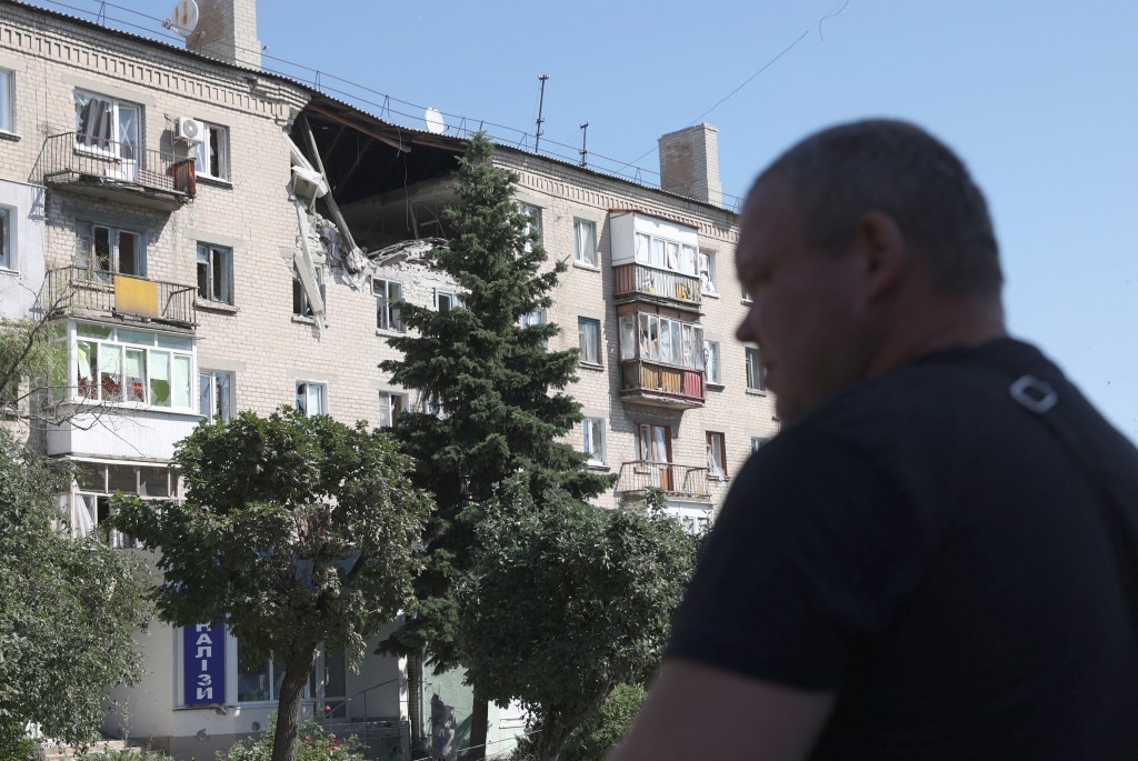 A man walks in front of damaged residential building on a street of the town of Lysychansk on June 21, 2022, amid the Russian invasion of Ukraine. (Photo by Anatolii Stepanov / AFP)