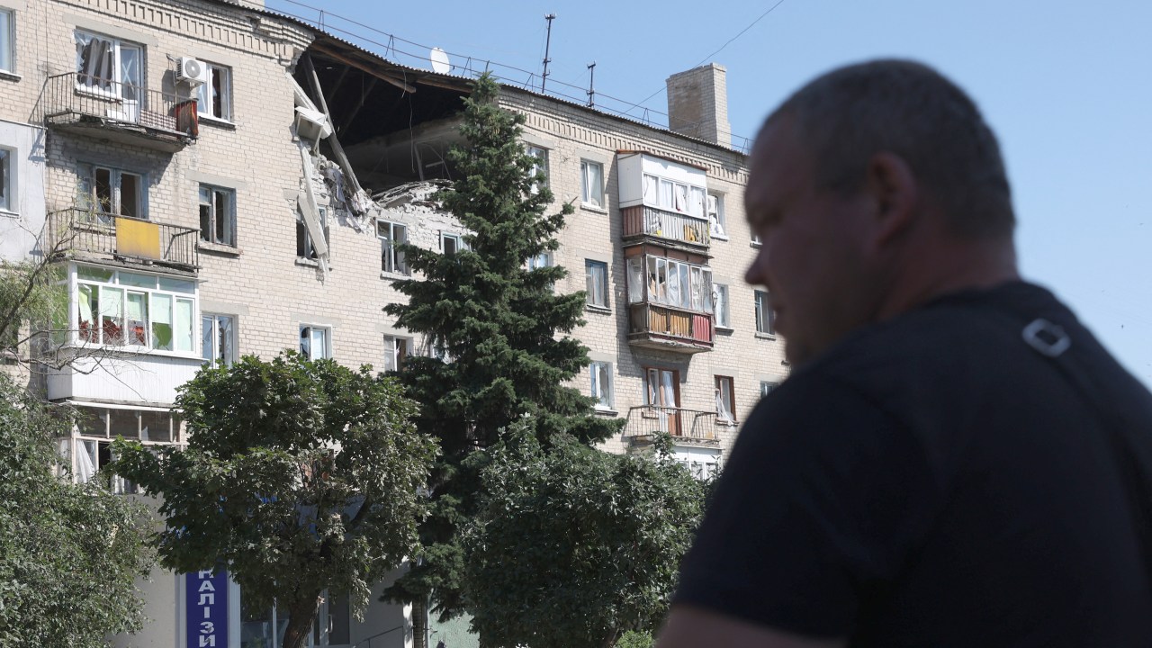 A man walks in front of damaged residential building on a street of the town of Lysychansk on June 21, 2022, amid the Russian invasion of Ukraine. (Photo by Anatolii Stepanov / AFP)