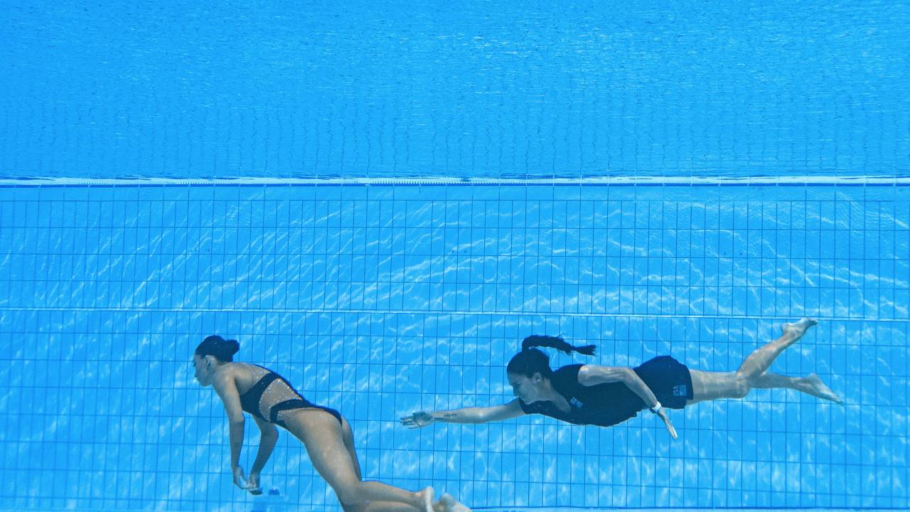 A member of Team USA (R) swims to recover USA's Anita Alvarez (L), from the bottom of the pool during an incendent in the women's solo free artistic swimming finals, during the Budapest 2022 World Aquatics Championships at the Alfred Hajos Swimming Complex in Budapest on June 22, 2022. (Photo by Oli SCARFF / AFP)
