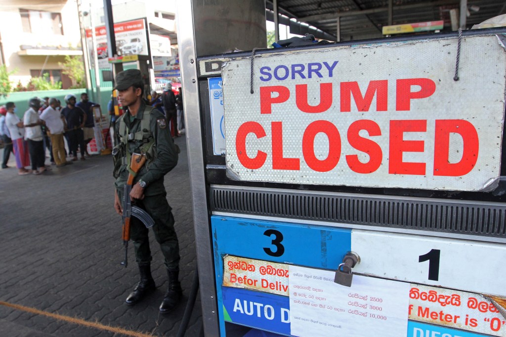 A member of Sri Lankan security personnel stands guard outside a fuel station that ran out of gasoline in Colombo on June 27, 2022. (Photo by AFP)