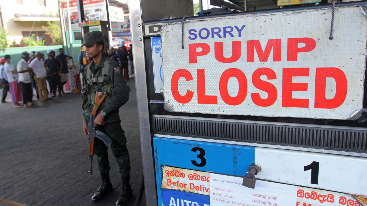 A member of Sri Lankan security personnel stands guard outside a fuel station that ran out of gasoline in Colombo on June 27, 2022. (Photo by AFP)