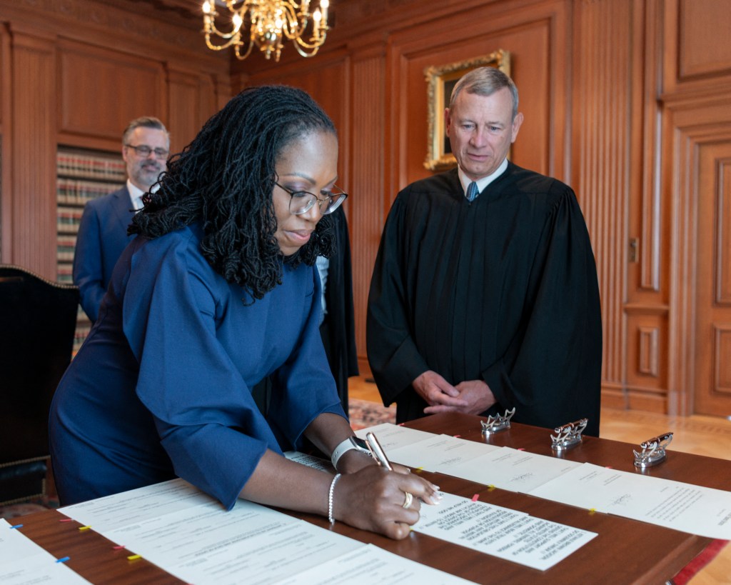 In this handout image released by the US Supreme Court, Chief Justice John G. Roberts, Jr., looks on as Justice Ketanji Brown Jackson signs the Oaths of Office in the Justices' Conference Room at the Supreme Court in Washington, DC, on June 30, 2022. - The United States made history on Thursday as Ketanji Brown Jackson was sworn in as the first Black woman to serve on the Supreme Court. (Photo by Handout / US Supreme Court / AFP) / RESTRICTED TO EDITORIAL USE - MANDATORY CREDIT "AFP PHOTO / US Supreme Court" - NO MARKETING NO ADVERTISING CAMPAIGNS - DISTRIBUTED AS A SERVICE TO CLIENTS