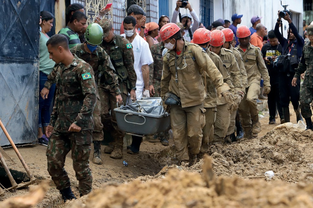 Firefighters and soldiers remove the body of a mudslide victim in the Jardim Monte Verde neighborhood of Recife in Pernambuco state, Brazil, Monday, May 30, 2022. Authorities in Pernambuco state said that at least 91 deaths have been confirmed from flooding over the weekend, with more than two dozen people still unaccounted for. (AP Photo/Joao Carlos Mazella)