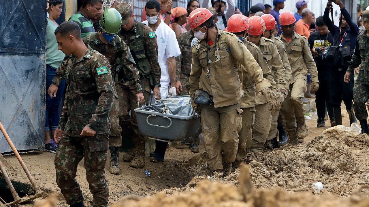 Firefighters and soldiers remove the body of a mudslide victim in the Jardim Monte Verde neighborhood of Recife in Pernambuco state, Brazil, Monday, May 30, 2022. Authorities in Pernambuco state said that at least 91 deaths have been confirmed from flooding over the weekend, with more than two dozen people still unaccounted for. (AP Photo/Joao Carlos Mazella)
