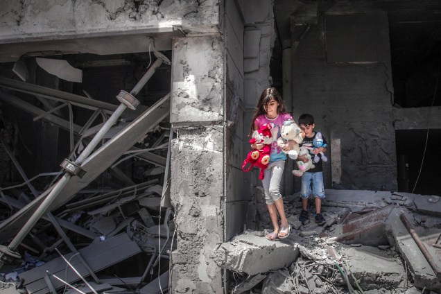 Crianças palestinas resgatam brinquedos de sua casa na Torre Al-Jawhara, na Cidade de Gaza, 2021.