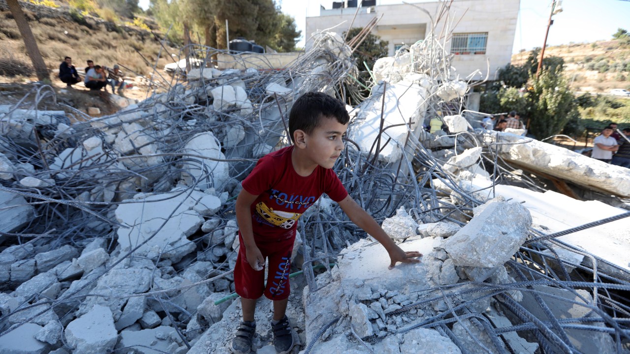 HEB20. HEBRON (GAZA E BANCO OESTE), 10/03/2019.- Uma criança palestina fica nos escombros de um prédio em construção danificado após a demolição de escavadeiras israelenses na vila de Biet Ommar, na Cisjordânia, ao norte de Hebron, 03 de outubro de 2019. O exército israelense demoliu regularmente edifícios palestinos na área C da Cisjordânia porque os palestinos não têm as licenças necessárias para construir. EFE/EPA/ABED AL HASHLAMOUN